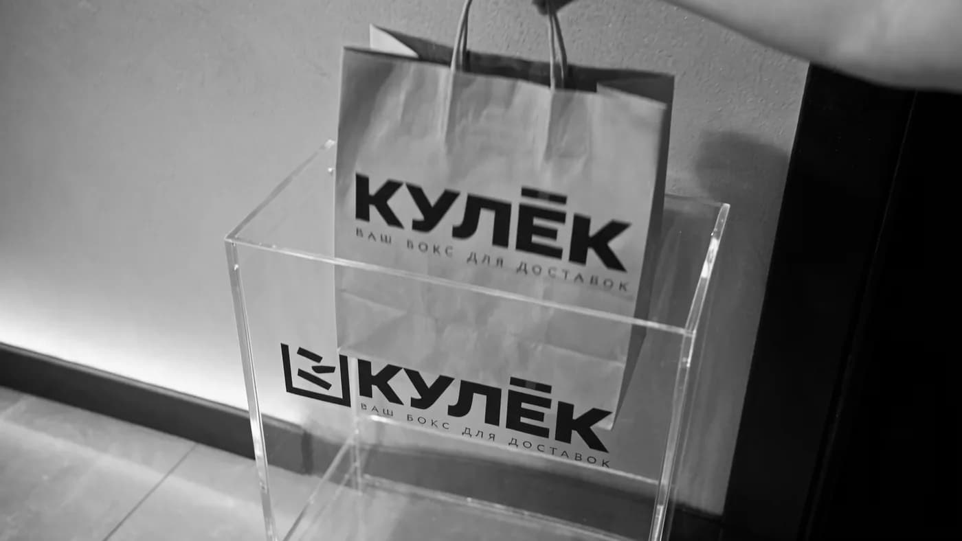 Курьер опускает бумажный пакет с покупками внутрь бокса